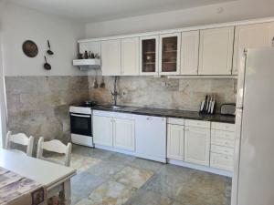 a white kitchen with white cabinets and a table at House Villa Oaza in Rogoznica