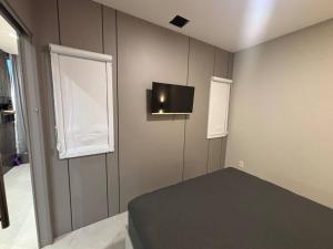 a bedroom with a bed and a tv on the wall at Apto com piscina aquecida perto do mar in Bombinhas +20 photos