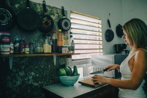 a woman standing in a kitchen using a laptop computer at La Casa del Kéej Hostel in Mérida
