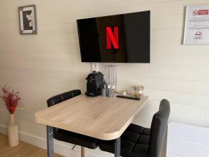 a dining room table with a tv on the wall at Studio moderne et tout équipé au cœur de Bourbourg - gare à proximité in Bourbourg