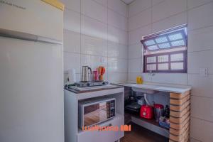 a white kitchen with a stove and a sink at Casa em São Sebastião a 5 min da Praia in São Sebastião