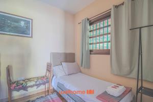 a bedroom with a bed and a chair and a window at Casa em São Sebastião a 5 min da Praia in São Sebastião