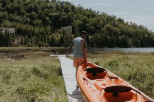 a man standing next to a boat on a dock at L'Echappee Belle - lake and SPA in Saint Come