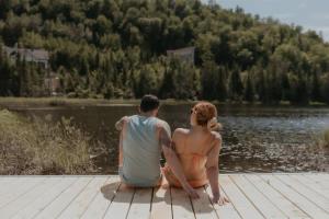 a man and woman sitting on a dock near a lake at L'Echappee Belle - lake and SPA in Saint Come +53 photos
