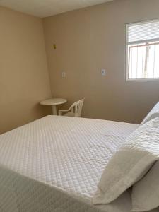 Una cama blanca grande en una habitación con ventana. en Casa De Temporada Mandacaru, en Piranhas