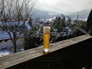 a glass of beer sitting on top of a wooden rail at Almhütte Schliersee in Schliersee