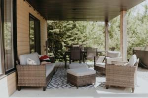 a screened in porch with wicker furniture and a table at L'Echappee Belle - lake and SPA in Saint Come