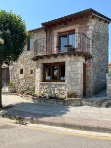 a stone building with a balcony on a street at La Herrería de Somo in Somo
