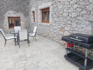 a grill on a patio with a table and chairs at La Herrería de Somo in Somo