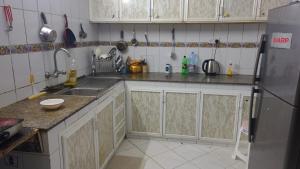 a kitchen with white cabinets and a stainless steel refrigerator at Muscat Galaxy Hostel in Muscat