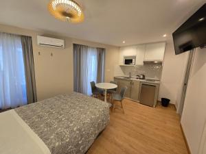 a bedroom with a bed and a table and a kitchen at Hostal Comercial in Madrid