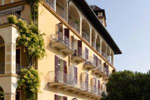 an apartment building with balconies and plants on it at Grand Hotel Fasano in Gardone Riviera