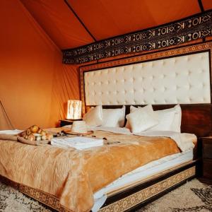 a bedroom with a large bed with a large headboard at Brilliant luxury camp in Merzouga