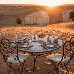 a table in the middle of the desert with a meal on it at Brilliant luxury camp in Merzouga