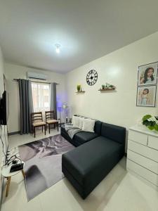 a living room with a couch and a clock on the wall at Staycation Calaca in Calaca