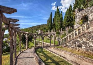 a garden with a stone wall and a pathway at Apartman Vasanija in Opatija
