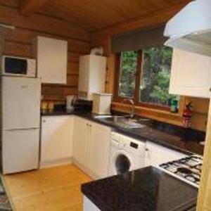 a kitchen with white cabinets and a black counter top at Hand built log cabin at Avonvale Holiday Lodges in Evesham