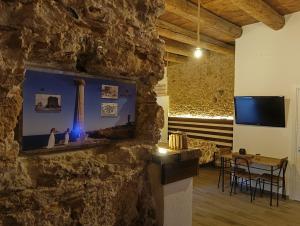 a room with a stone wall with a tv and a table at Re carlo suite & spa in Crotone