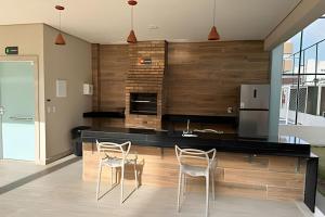 a kitchen with a counter with chairs and a refrigerator at Apartamento na praia, 2 quartos e área de lazer in Cabedelo