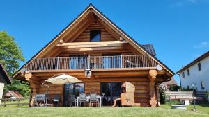 a log cabin with a balcony and tables and chairs at Holzhaus Usedom mit moderner Ausstattung SAUNA und Kamin in Karnin (Usedom)