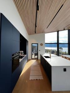 une cuisine avec des armoires en noir et blanc et une grande fenêtre dans l'établissement Efjord and Stetind Resort - Cabin Stetind, à Ballangen