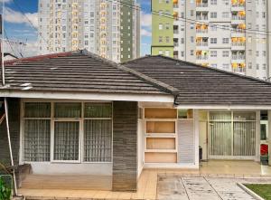 a small house in front of some tall buildings at Large Villa 3BR Cieumbuleuit near PVJ & Cihamplas by 2ndHome in Bandung