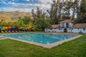 a swimming pool with chairs and umbrellas in a yard at Hacienda los Lingues Chile Valle de Colchagua in Los Lingues