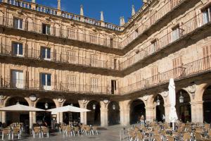 a building with tables and chairs in front of it at El capricho Balcón en la Plaza Mayor Salamanca Collection Luxury in Salamanca