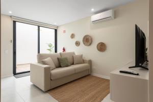a living room with a couch and a television at Villa 41 - Private Studios Faro Airport, Beach and City Center in Faro