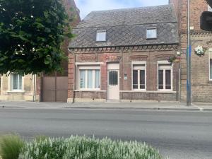 a brick house with a white door on a street at Le gîte du familistère -399 in Guise