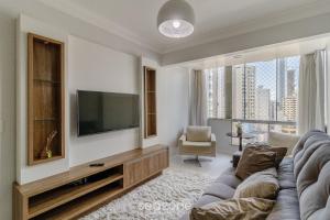 a living room with a couch and a flat screen tv at Apto vista mar c/ churrasq. na orla BC CET1604 in Balneário Camboriú