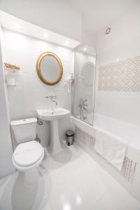 a white bathroom with a toilet and a sink at Małopolanka & Spa in Krynica Zdrój