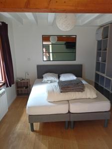 a bedroom with a bed with white sheets and a window at Chambre d'hôte 4 couchages in Thorigné-sur-Dué