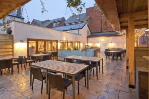 een patio met tafels en stoelen en een gebouw bij The Queen Hotel Wetherspoon in Aldershot