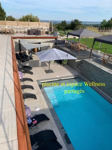 a swimming pool with umbrellas and lounge chairs next to it at Durbuy House gîte verger in Durbuy