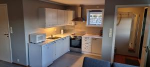 a kitchen with white cabinets and a sink and a window at Sokkelleilighet på Kolnes in Tananger