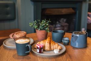 einen Tisch mit einem Teller Essen und Tassen Kaffee in der Unterkunft The Lazy Goose - Coffee House & Bedrooms in Stonehouse
