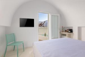 Un dormitorio blanco con una cama y una silla azul. en Santorini Sun Villas, en Oia