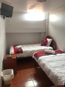 una stanza con due letti e una televisione di Hotel TIKA AYNA Cerca a la plaza de Armas CUSCO a Cuzco Altre 98 foto