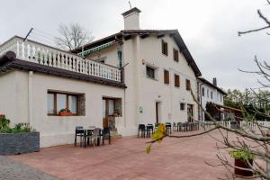 a building with tables and chairs in front of it at Casa Rural Altzibar-berri in Urnieta