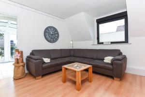 a living room with a couch and a clock on the wall at Ferienhaus Boje 13 in Neuharlingersiel