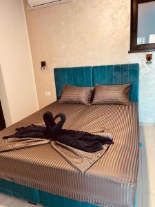 a bed with a blue headboard with a robe on it at Neversea Boutique Villa in Constanţa