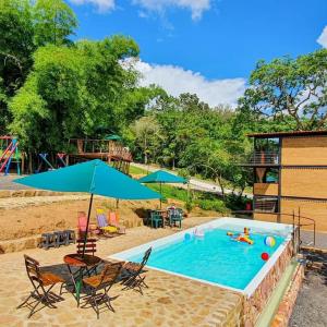 a swimming pool with chairs and a blue umbrella at Villas del bambú in San Gil