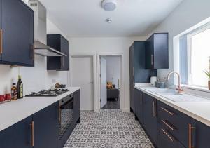 une cuisine avec des comptoirs blancs et des armoires bleues dans l'établissement Sedgley-wolverhampton-contractors -4 Beds-parking, à Sedgley