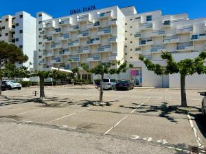 ein Parkplatz vor einem großen Gebäude in der Unterkunft *Au Lydia* Appartement vue sur mer, avec piscine. in Le Barcarès