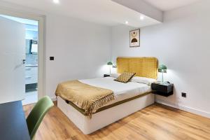 a white bedroom with a bed and a chair at Apartamentos Beatriz by gaiarooms in Salamanca