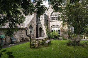 une table de pique-nique et un banc devant un bâtiment dans l'établissement Large Grade II Listed House & Garden nr Beaches, à Saint Columb Major