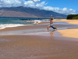 a person jumping in the air on a beach at Kihei Akahi Resort - Unit D114 in Wailea