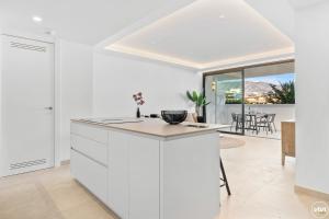 a white kitchen with a counter and a dining room at ViVi Homes - Jade Beautiful Apartment with Spa, Pool and Cinema 200 meters from the beach in Fuengirola