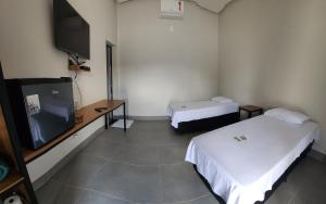 a room with two beds and a flat screen tv at Hotel friper in Jaraguá